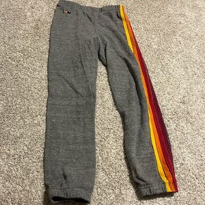 Aviator Nation grey sweatpants with colorful stripes down one leg.